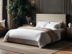 Chenille ottoman bed with horizontal panel headboard and lift-up storage base in a modern bedroom with dark walls and wooden flooring.
